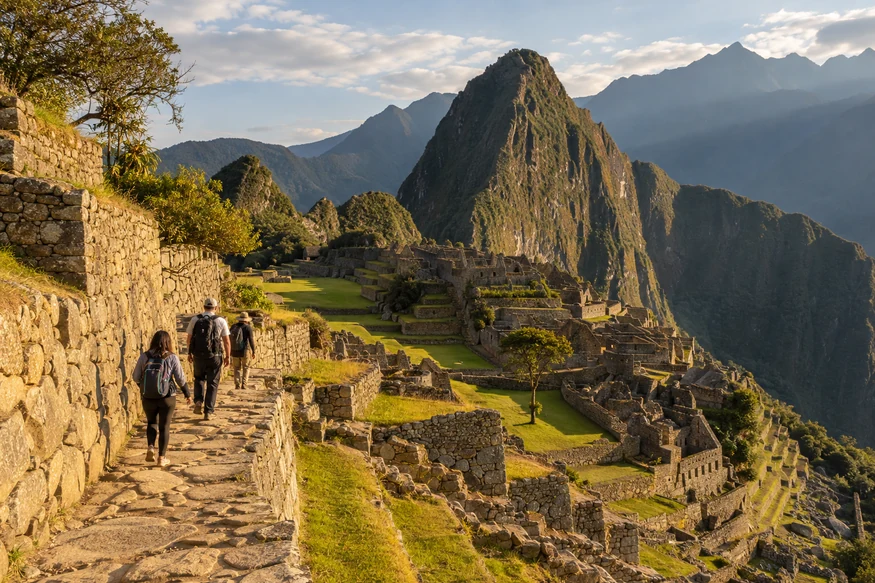 Travelers walking through Machu Picchu in warm late-afternoon light